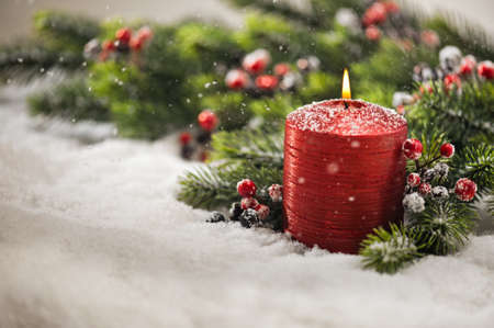 Candle in snow and with christmas tree branches decoratedの写真素材
