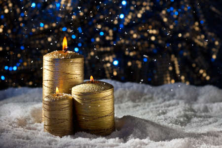 Golden Candles in snow and Christmas settingの写真素材