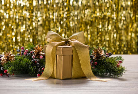 Gold present and Christmas tree branches in front of golden backgroundの写真素材