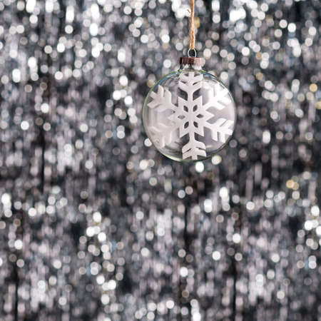 Snow flake Christmas bauble over silver glitter backgroundの写真素材