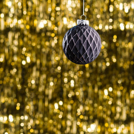 Black Christmas tree bauble over gold glitter backgroundの写真素材