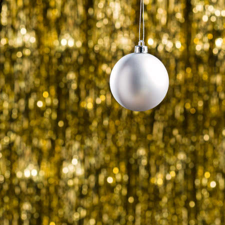 White Christmas bauble ornament over gold glitter backgroundの写真素材