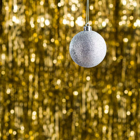 Silver christmas tree ornament over gold glitter backgroundの写真素材