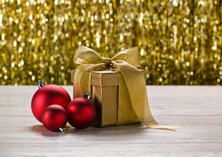 Gold present and red bauble in front of golden backgroundの写真素材