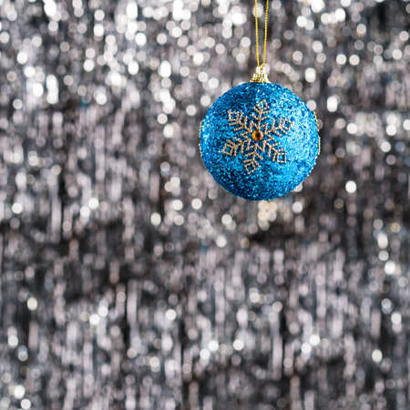 Blue christmas bauble ornament over silver glitter backgroundの写真素材