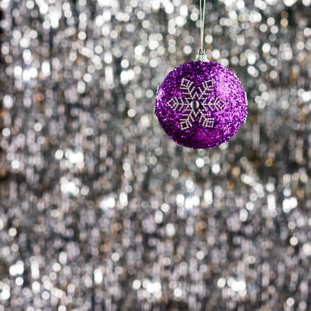 Purple christmas bauble over silver glitter backgroundの写真素材