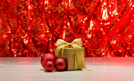 Gold present with red bauble in front of a sparkling backgroundの写真素材