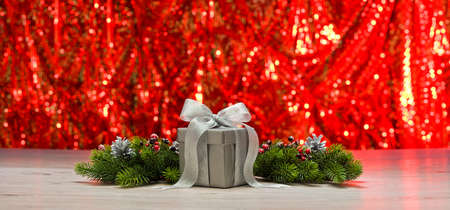 Silver present and Christmas tree branches in front of a sparkling backgroundの写真素材