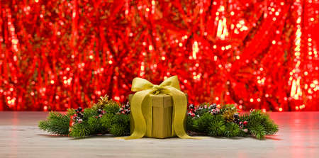 Gold present and Christmas tree branches in front of a sparkling backgroundの写真素材