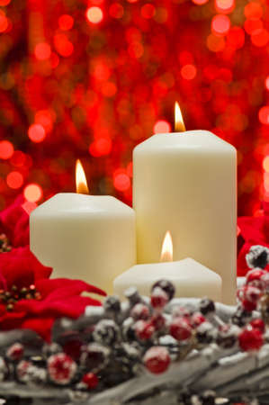 White candles in autumn winter decoration in front of a red backgroundの写真素材