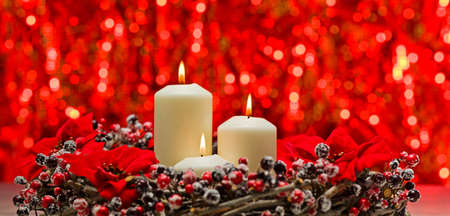 White candles in autumn winter decoration in front of a red backgroundの写真素材