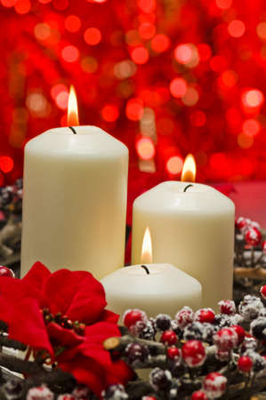 White candles in autumn winter decoration in front of a red backgroundの写真素材