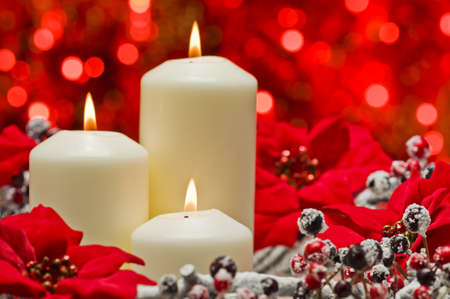 White candles in autumn winter decoration in front of a red backgroundの写真素材