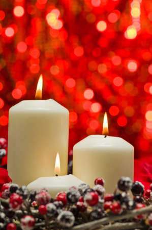 White candles in autumn winter decoration in front of a red backgroundの写真素材