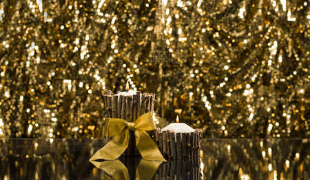 Two candles with gold ribbon in front of a sparkling backgroundの写真素材