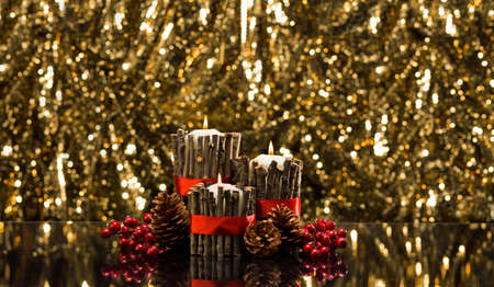 White candles in autumn winter decoration in front of a golden backgroundの写真素材