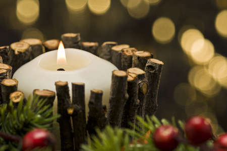 White candle in autumn winter decoration in front of a golden backgroundの写真素材