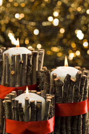 White candles in autumn winter decoration in front of a golden backgroundの写真素材