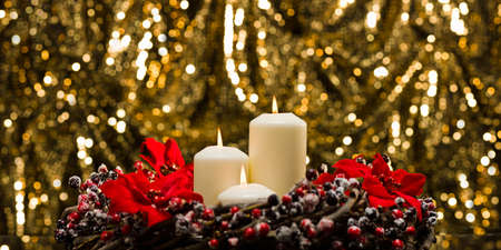 White candles in autumn winter decoration in front of a golden backgroundの写真素材