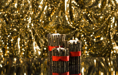 White candles in autumn winter decoration in front of a golden backgroundの写真素材