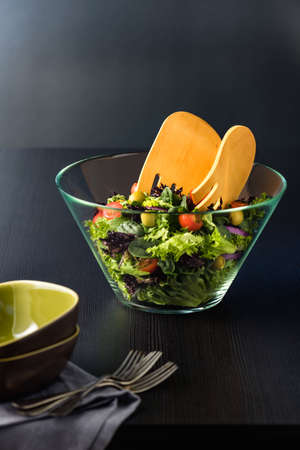 Green salad in glass bowl on a dark tableの写真素材