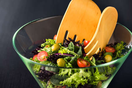 Green salad in glass bowl on a dark tableの写真素材