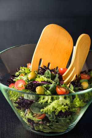 Green salad in glass bowl on a dark tableの写真素材