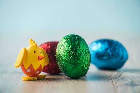 Chicken figurine, red, green and blue easter egg on a white tableの写真素材