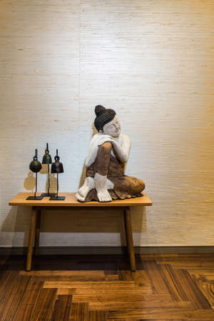 Buddha on a side table in a room with beautiful parquet flooringの写真素材