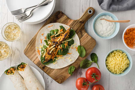 Fresh healthy chargrilled tandoori chicken wrap with tzatziki, cheese, baby spinach and carrotsの写真素材