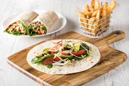 shredded barbecued chicken wraps with carrot, cheese, avocado and spinach. With French fries on the side.の写真素材