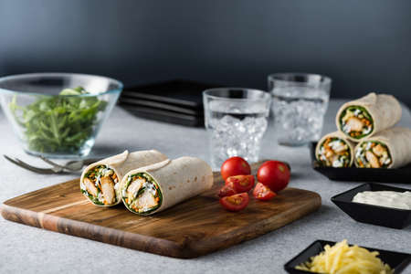 Fresh healthy chargrilled tandoori chicken wrap with tzatziki, cheese, baby spinach and carrotsの写真素材