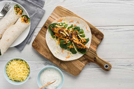 Fresh healthy chargrilled tandoori chicken wrap with tzatziki, cheese, baby spinach and carrotsの写真素材