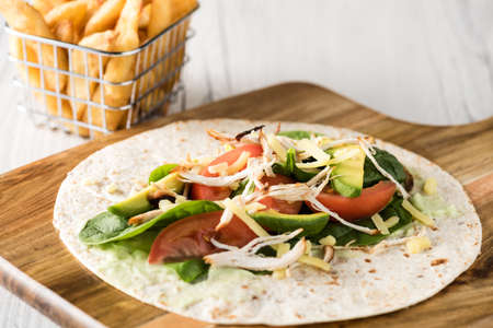 shredded barbecued chicken wraps with carrot, cheese, avocado and spinach. With French fries on the side.の写真素材