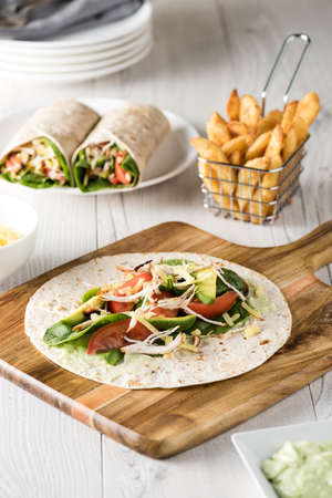 shredded barbecued chicken wraps with carrot, cheese, avocado and spinach. With French fries on the side.の写真素材