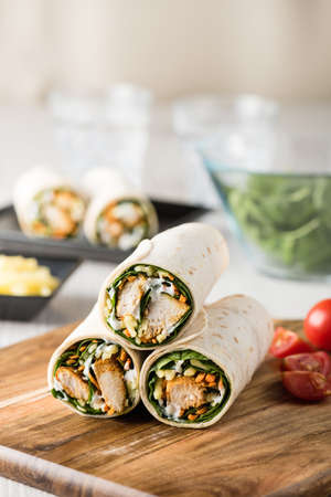 Fresh healthy chargrilled tandoori chicken wrap with tzatziki, cheese, baby spinach and carrotsの写真素材