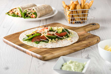 shredded barbecued chicken wraps with carrot, cheese, avocado and spinach. With French fries on the side.の写真素材