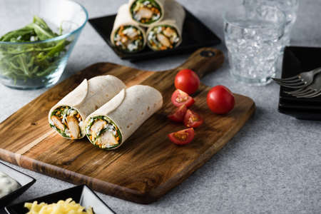 Fresh healthy chargrilled tandoori chicken wrap with tzatziki, cheese, baby spinach and carrotsの写真素材