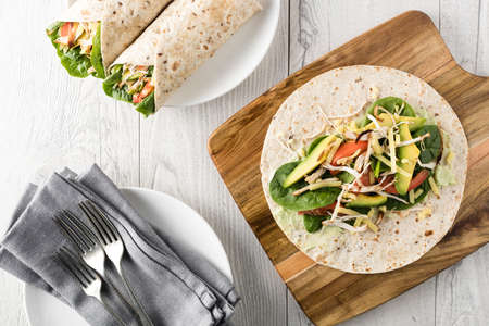 shredded barbecued chicken wraps with carrot, cheese, avocado and spinach. With French fries on the side.の写真素材