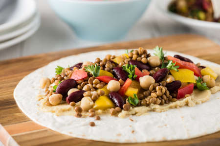 Vegan wraps with lentil, chickpea, kidney bean, peppers and hummus sauceの写真素材