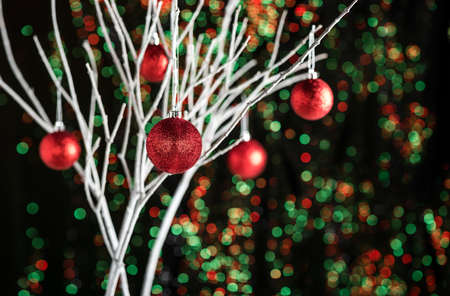White twigs with Christmas tree baubles in front of a green red backgroundの写真素材