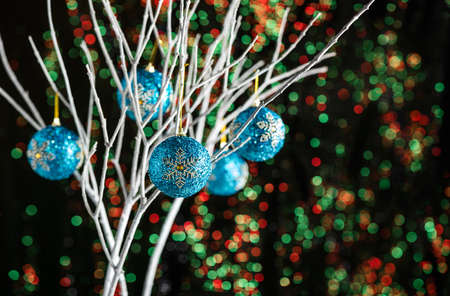 White twigs with Christmas tree baubles in front of a green red backgroundの写真素材