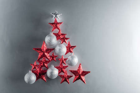 Christmas tree shape with red stars and silver baubles over color backgroundの写真素材