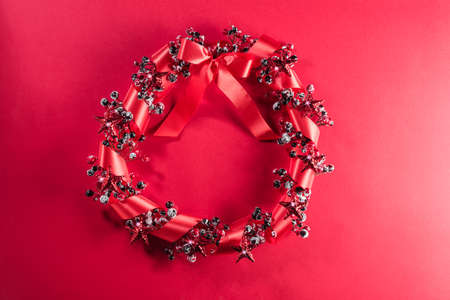 Christmas wreath in red with ribbon over plain color backgroundの写真素材