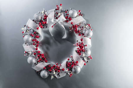 Christmas wreath in red with silver ribbon over plain color backgroundの写真素材