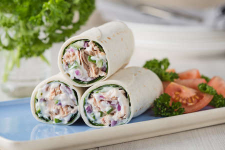 Tuna wraps with cucumber onion and mayonnaise with tomato saladの写真素材