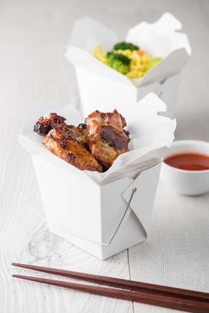 Asian chicken wings and noodles in take-out box with dipping sauceの写真素材