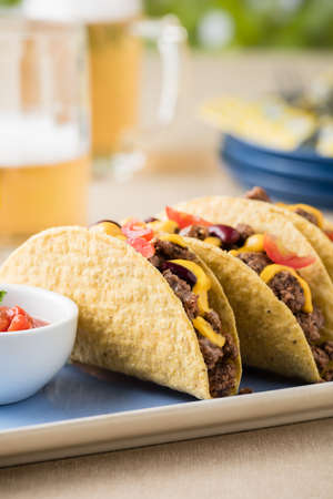 Mexican tacos with beef, cheddar cheese, tomato, beans and salsa dips at beer gardenの写真素材