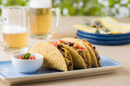 Mexican tacos with beef, cheddar cheese, tomato, beans and salsa dips at beer gardenの写真素材