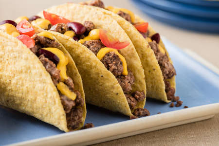 Mexican tacos with beef, cheddar cheese, tomato, beans and salsa dipsの写真素材